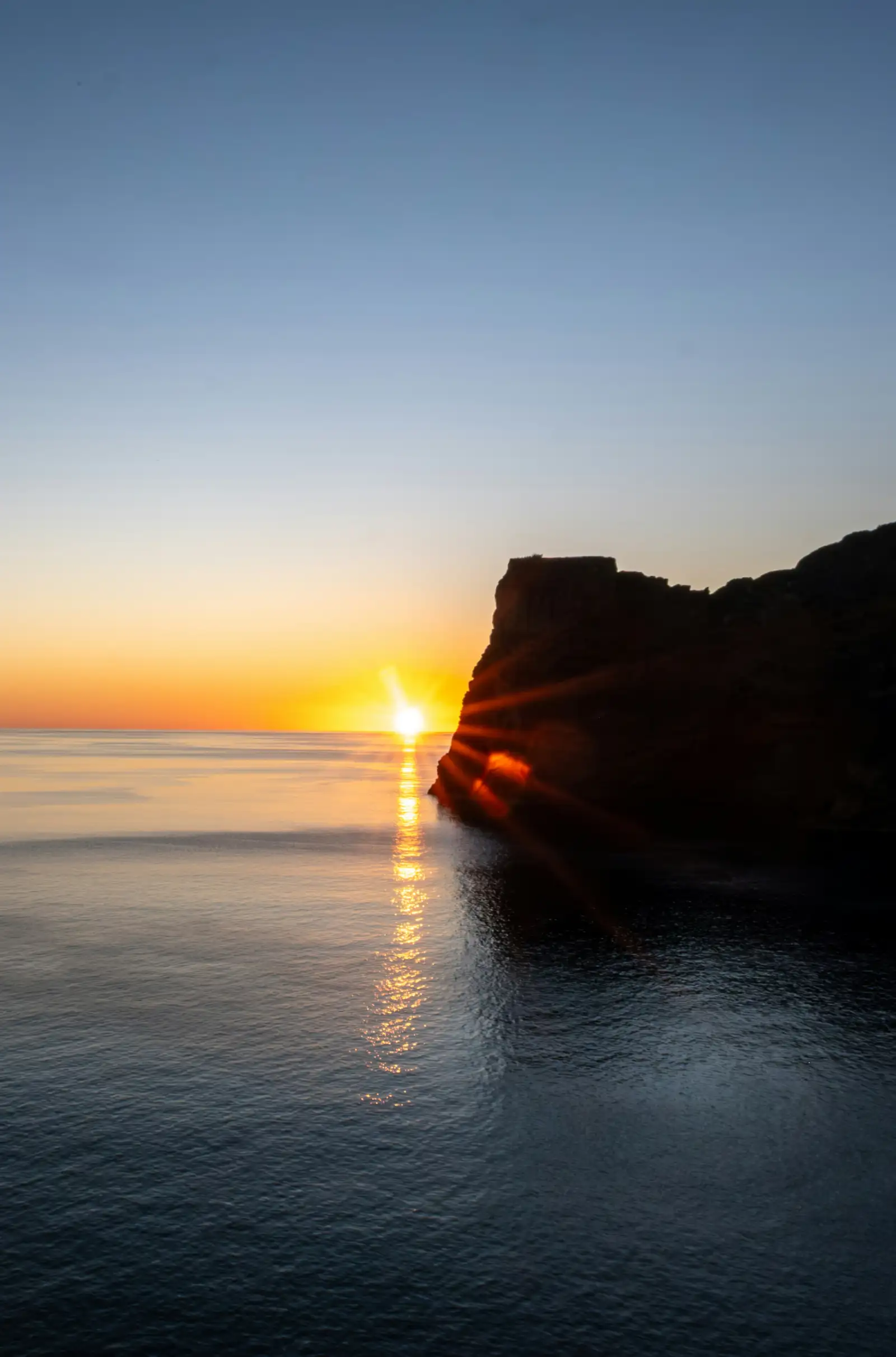 Sun setting behind a sea cliff